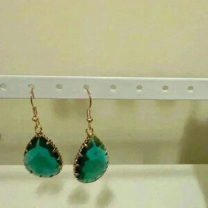 teardrop-shaped with a vibrant green gemstone or stone-like centerpiece